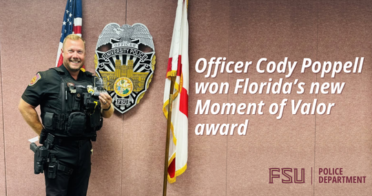 A police officer smiles proudly, standing next to an American flag and a police emblem on the wall. Text: 'Officer Cody Poppell won Florida's new Moment of Valor award.'